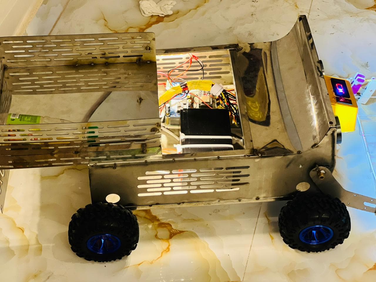 Top-down view of the rover showing the stainless chassis, cargo bed and blue-rimmed wheels